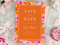 an orange and pink floral wedding save the date card on top of some peonies