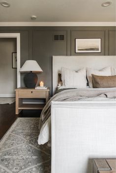 a bedroom with a bed, night stand and lamp on the end table in front of it