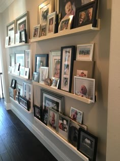 a wall filled with lots of framed pictures on top of wooden shelves next to a doorway