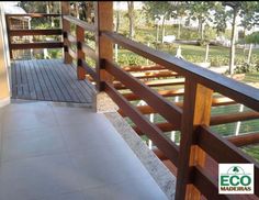 a balcony with wooden railings and tiled flooring next to a tree lined yard