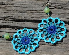 crocheted earrings with blue and green beads on wooden planks, closeup