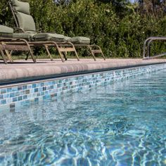 an empty swimming pool with lounge chairs next to it