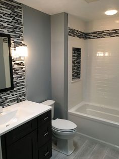 a white toilet sitting under a bathroom mirror next to a bathtub and sink in a bathroom