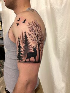 a man with a deer and trees tattoo on his arm