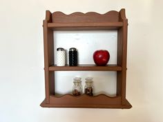 two wooden shelves with jars and an apple on top