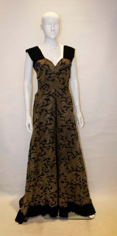 For Sale on 1stDibs - A headturning vintage evning gown in a heavy black and gold fabric with black velvet trim. The dress has black velvet strap and hem and a side zip. Brocade Evening Dress With Fitted Bodice, Evening Dress With Fitted Brocade Bodice, Evening Dress With Fitted Bodice In Brocade, Fitted Brocade Evening Dress, Vintage Black Evening Dress With Fitted Bodice, Elegant Brocade Evening Dress, Gold Velvet Evening Dress, Formal Floor-length Brocade Evening Dress, Vintage Gold Evening Dress For Gala