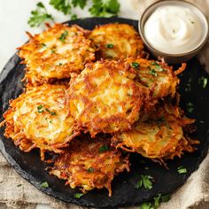 some food is sitting on a black plate with sour cream in the bowl and garnished with parsley