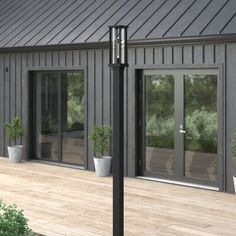 a wooden deck with potted plants on it and two large windows in the background