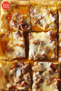 several square pieces of pizza sitting on top of a wooden cutting board with cheese and meat toppings