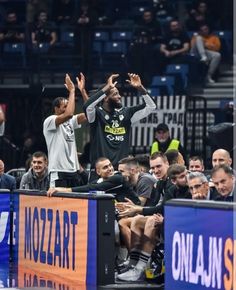 two basketball players high fiving on the sidelines at a game with their hands in the air