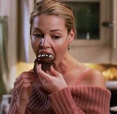 a woman eating a chocolate doughnut in the kitchen