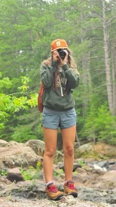 a woman standing on top of a rock while taking a photo with her cell phone