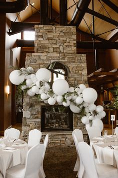 a room filled with tables covered in white tablecloths and balloons hanging from the ceiling