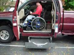 a man in a wheel chair sitting in the back of a red pickup truck with its door open