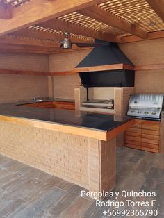 an outdoor kitchen with grill and counter top in the middle of wood floored area