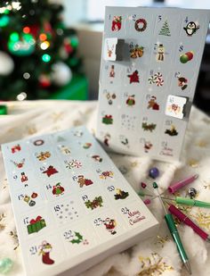 two christmas stickers on top of a white box next to a green christmas tree