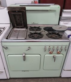 an old fashioned stove with two burners and one oven door open, in a kitchen