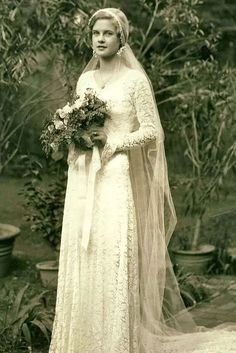 an old black and white photo of a woman in a wedding dress holding a bouquet