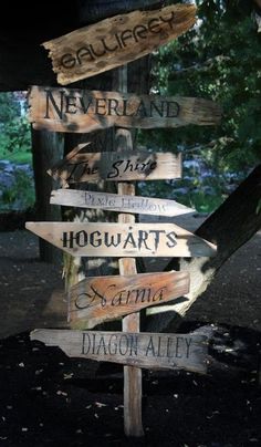 a wooden sign with many different signs on it's side in front of a tree