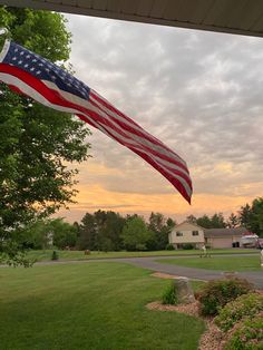 an american flag is flying in the wind on a house's front lawn at sunset