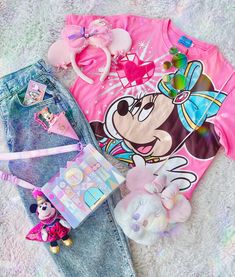 a minnie mouse shirt, jeans and other items are laying on the floor next to each other