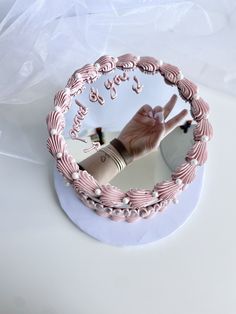 a cake decorated with pink icing and writing on the top is being held up in front of a mirror