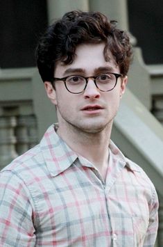 a man wearing glasses standing in front of stairs