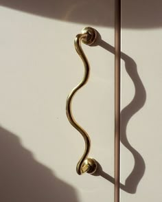 a gold handle on the side of a white wall next to a light fixture and shadow