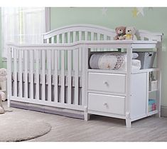 a white crib with two drawers and a teddy bear on the top shelf next to it