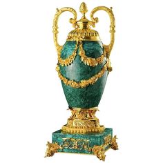 a green and gold vase sitting on top of a table