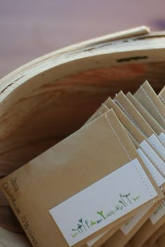 a wooden basket filled with lots of brown envelopes next to a pile of cards