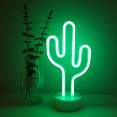 a neon green cactus lamp sitting next to a bottle