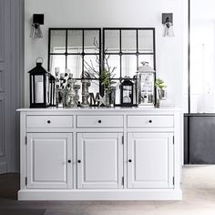 a white dresser with mirrors and vases on it