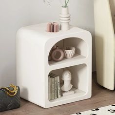 a white shelf with books and vases on it