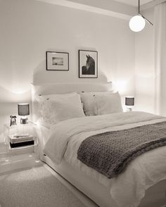 a bedroom with white bedding and pictures on the wall above it, along with two nightstands