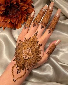 a woman's hand with henna on it and a flower in the background