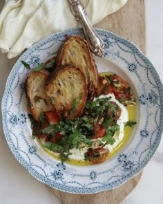 a white and blue plate topped with toasted bread next to a bowl of salad