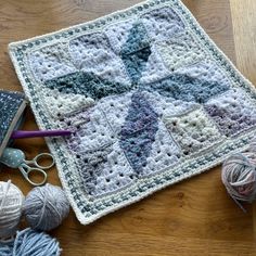 a crocheted granny blanket with yarn and scissors on the floor next to it