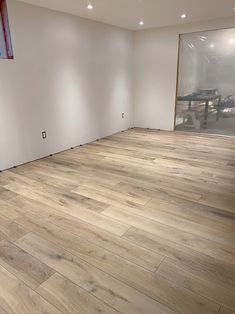 an empty room with white walls and wood floors