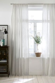 a window with white curtains and a potted plant