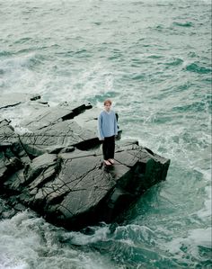 a man standing on top of a rock in the ocean