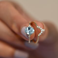 a woman's hand holding an engagement ring with a blue topazte and white diamonds