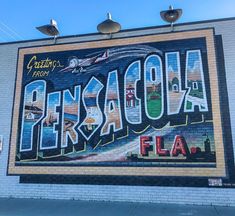 a woman standing in front of a mural on the side of a building with an airplane flying over it