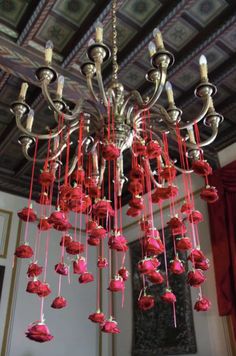 a chandelier with red roses hanging from it's sides in a room