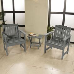 two blue chairs sitting next to each other on a tile floor in front of windows