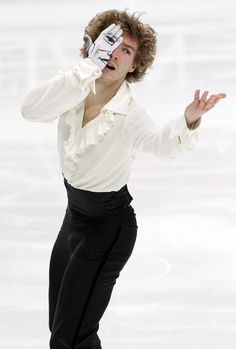 a man in white shirt and black pants skating on ice with his hands out to the side