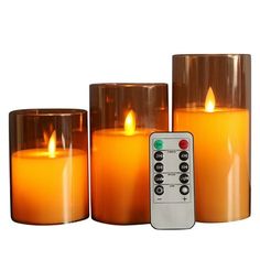 three lit candles with remote controls in front of them