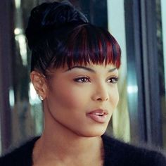 a close up of a person wearing a black top and hair in a bun with red highlights