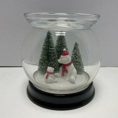 a snow globe with two small trees and a polar bear in red hat on it