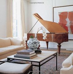 a living room filled with furniture and a grand piano in the corner on top of a coffee table